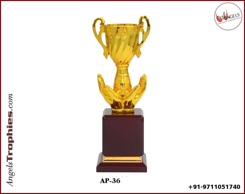 metal golden cup with golden hand with wooden base